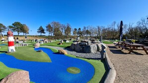 Un parque con un faro, mesas de picnic y un camino azul serpenteante.
