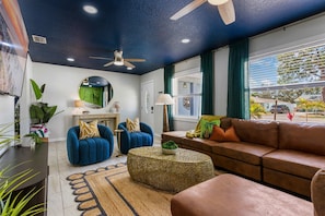 A living room with a ceiling fan, a round coffee table, a brown sofa, and a blue armchair. - 5BR, HtdPool, Pickleball, FootPool, 8 min to Beach (Bradenton)
