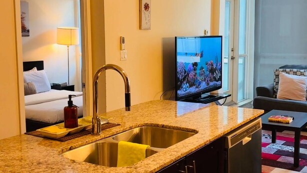 Une chambre d’hôtel équipée d’un coin cuisine, d’un téléviseur diffusant des images du monde sous-marin, d’un lit et offrant une vue sur l’extérieur.