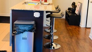 Une cuisine équipée d’un évier, d’une petite poubelle et d’un tabouret de bar.