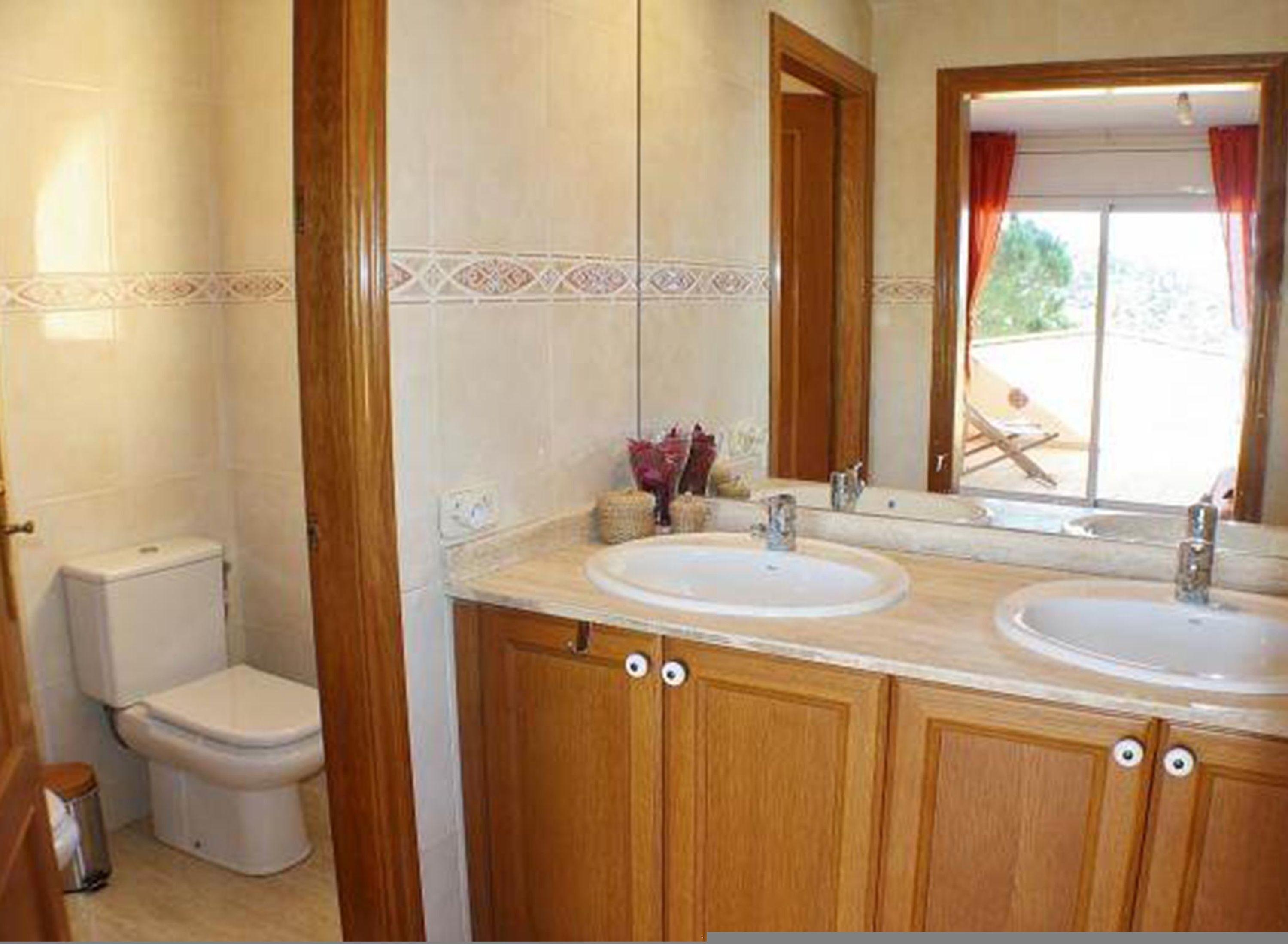 Un baño con dos lavamanos, un inodoro y un espejo.