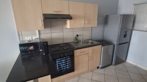 A kitchen with a black countertop, stainless steel appliances, and light-colored cabinets. - Serene 1-bedroom Apartment in Bloemfontein (Bloemfontein)