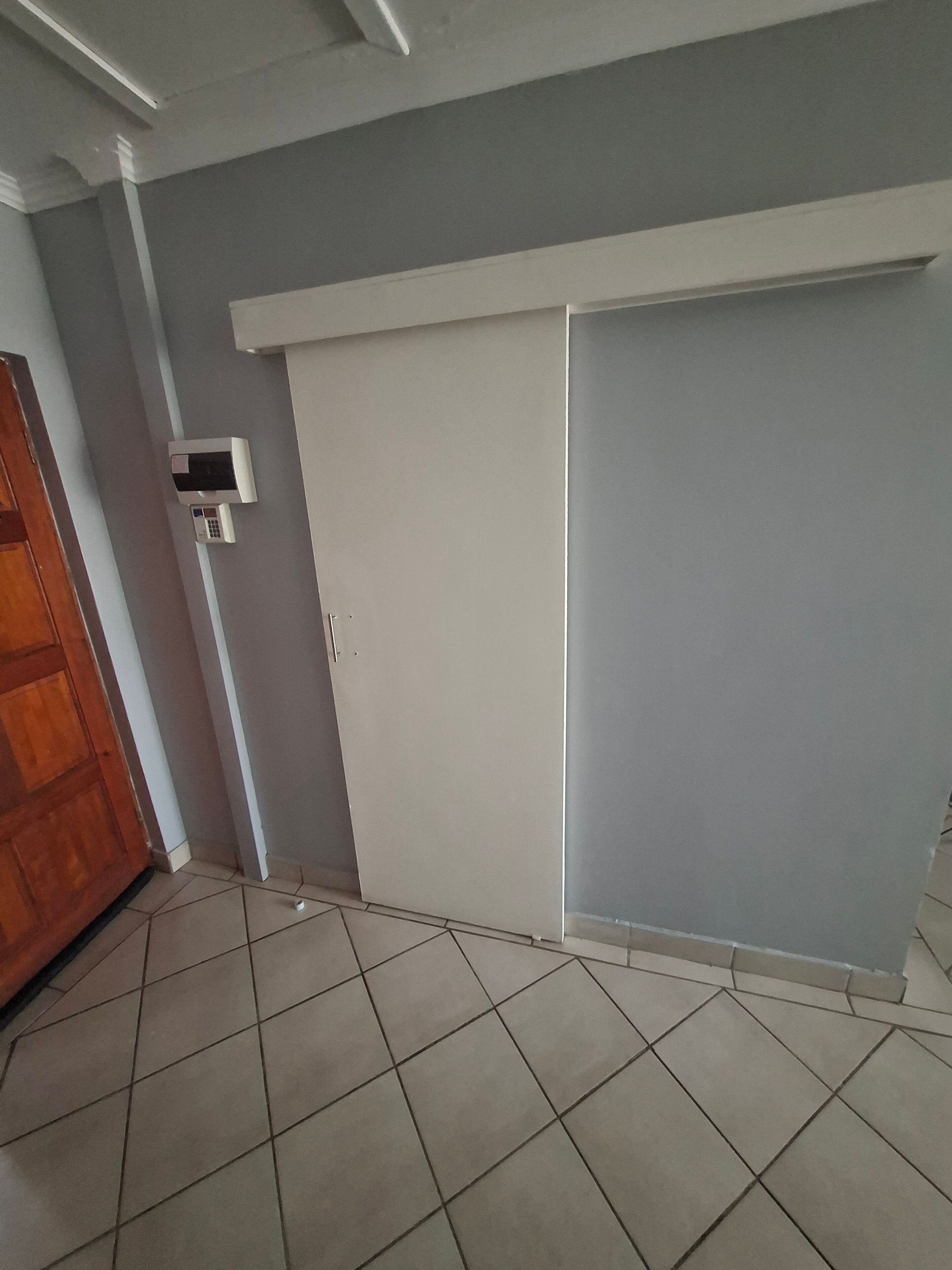 A room with a sliding door, a wall-mounted air conditioning unit, and a tiled floor.