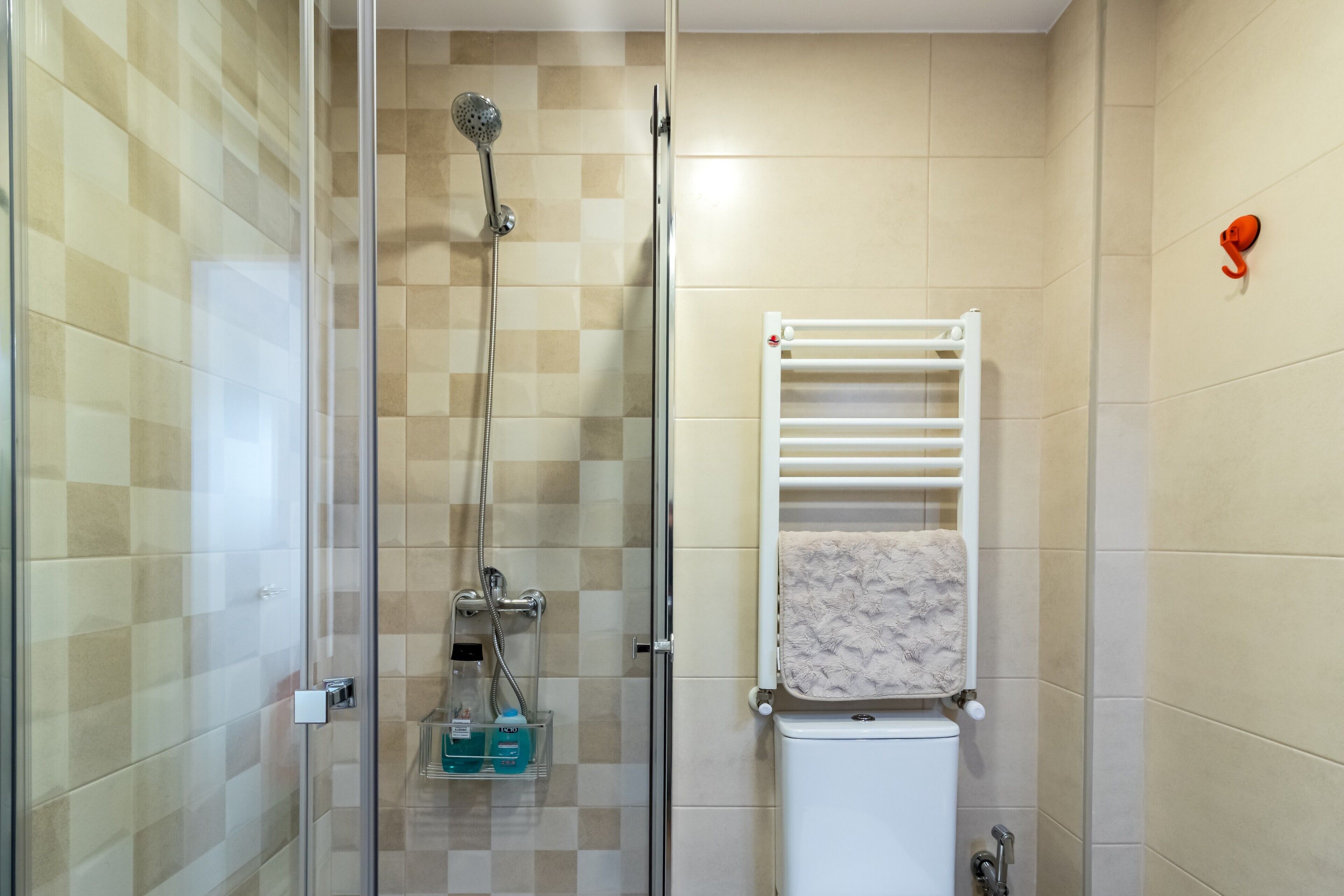 Ein Badezimmer mit Duschkabine aus Glas, einer weißen Toilette und einem Handtuchhalter mit gefaltetem Handtuch.