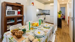 A compact kitchen with a microwave, refrigerator, and dining area set for a meal.
