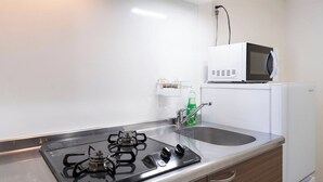 Et tekøkken med gasblus, vask, mikroovn og lille køleskab.
