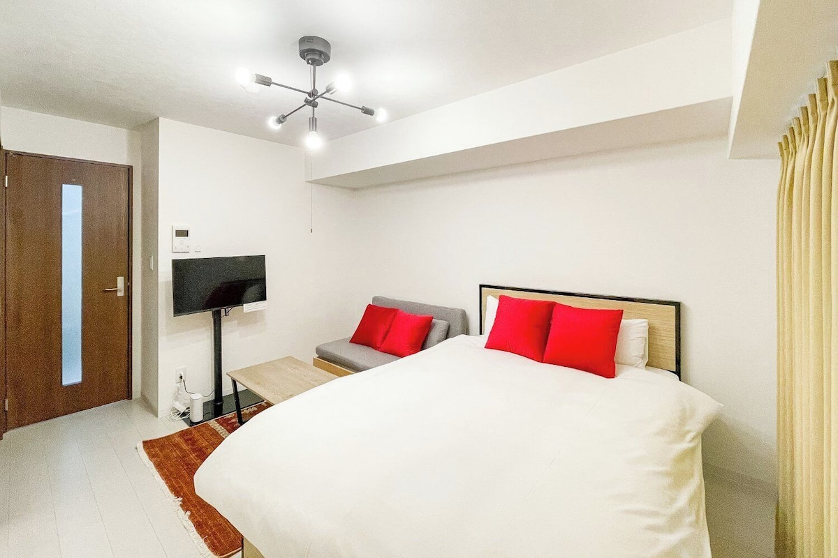 A hotel room with a bed, a TV, a desk, and a ceiling fan.