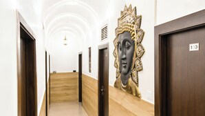 A hallway with wooden paneling, a Buddha statue, and doors numbered 103. - Hotel Pardesi's Near Mansa Devi Temple (Haridwar)