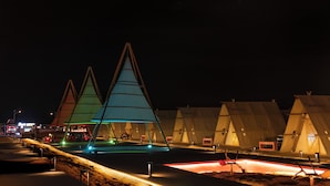 Una hilera de tiendas de campaña con una estructura iluminada en el centro.