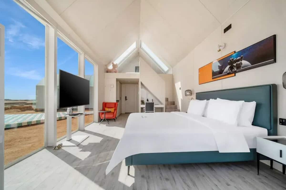 Une chambre d’hôtel moderne équipée d’un grand lit, d’une télévision, d’un bureau et d’une chaise.