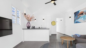 Eine moderne Küche mit einer zentralen Kochinsel, einem Flachbildfernseher, einem Deckenventilator und einem Gemälde einer Meeresschildkröte.