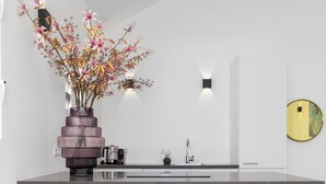 Eine moderne Küche mit einer zentralen Kochinsel, einem Blumenstrauß und einem runden Spiegel an der Wand.