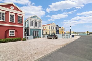 A row of colorful houses with a gravel driveway and a parked car. - Bon Bida di Watervillas #48b (Kralendijk)