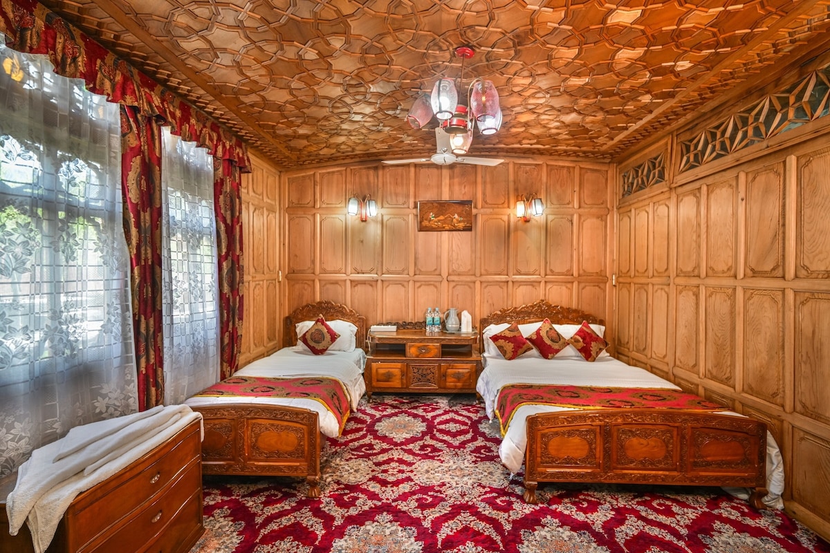 Quarto com duas camas de madeira, um ventilador de teto, cômoda de madeira e tapete estampado.