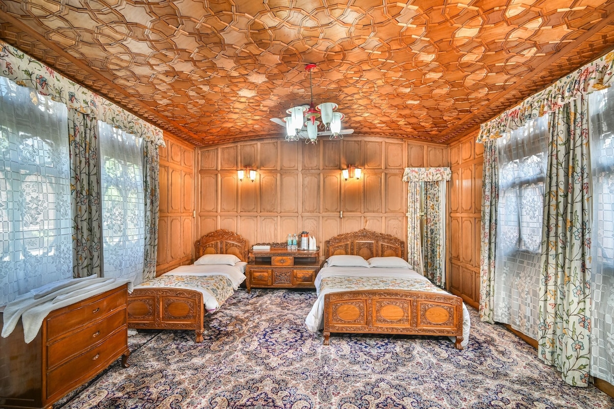 Quarto com duas camas de madeira, um candelabro e cortinas estampadas.