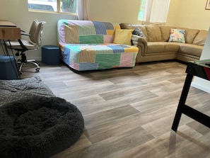 A living room with a sofa, a chair, a fluffy ottoman, a small table, and a window with curtains. - 'Seas the Day' Preston Beach | Pet Friendly | Sleeps 6 | 500m to the beach! (Preston Beach)