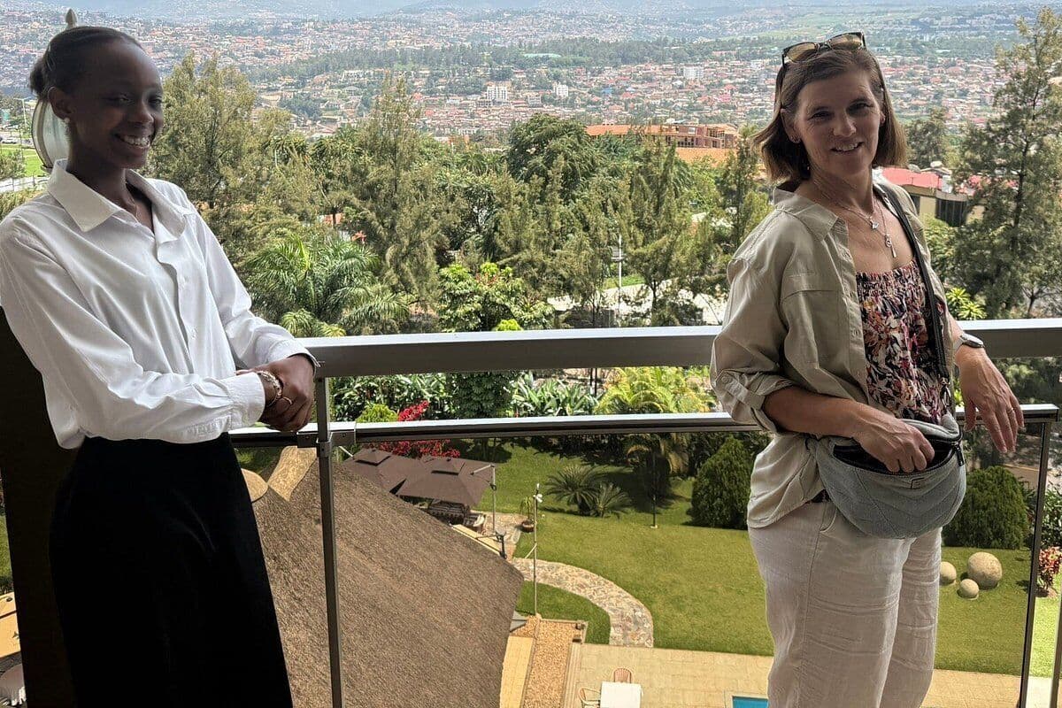 Deux personnes se tiennent sur un balcon, avec une vue sur le paysage urbain.
