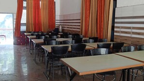 A dining area with tables and chairs, a tiled wall, and a window with curtains. - Chandresh Homestay (Aut)