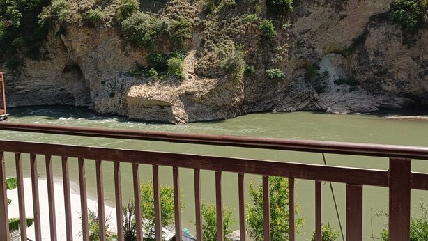 A river with a rocky cliff and greenery. - Chandresh Homestay (Aut)