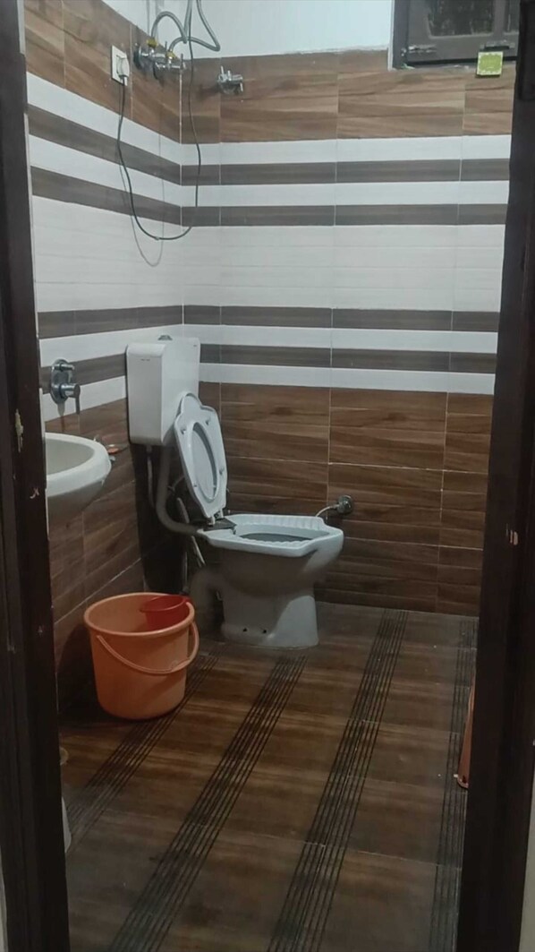 A bathroom with a toilet, sink, and a bucket.