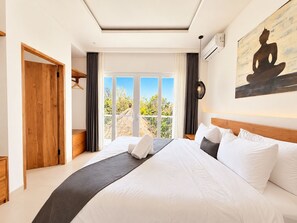 Ein Schlafzimmer mit einem großen Bett, Blick ins Freie und einem Gemälde an der Wand.