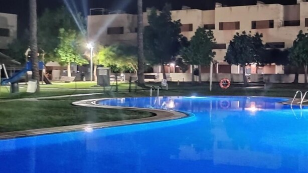 A swimming pool with a circular design, surrounded by palm trees and a building with multiple windows. - Relax & Play Panoramic Golf Vinaroz (Sant Jordi)