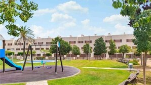 A playground with swings and a slide, surrounded by a grassy area and trees. - Relax & Play Panoramic Golf Vinaroz (Sant Jordi)