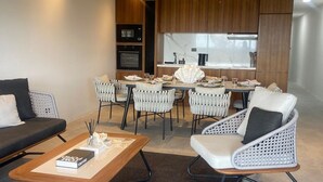 Un salon moderne comprenant un canapé, des fauteuils, une table basse et un coin repas avec une table et des chaises.