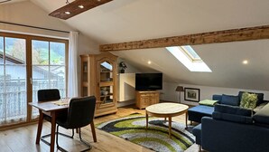 Ein Loft-Wohnzimmer mit Essbereich, Fernseher und Dachfenster.