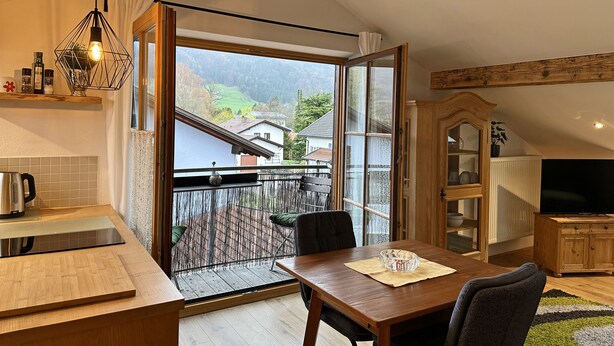 Eine moderne Küche mit Essbereich, einem Holzschrank und einem Fernseher.