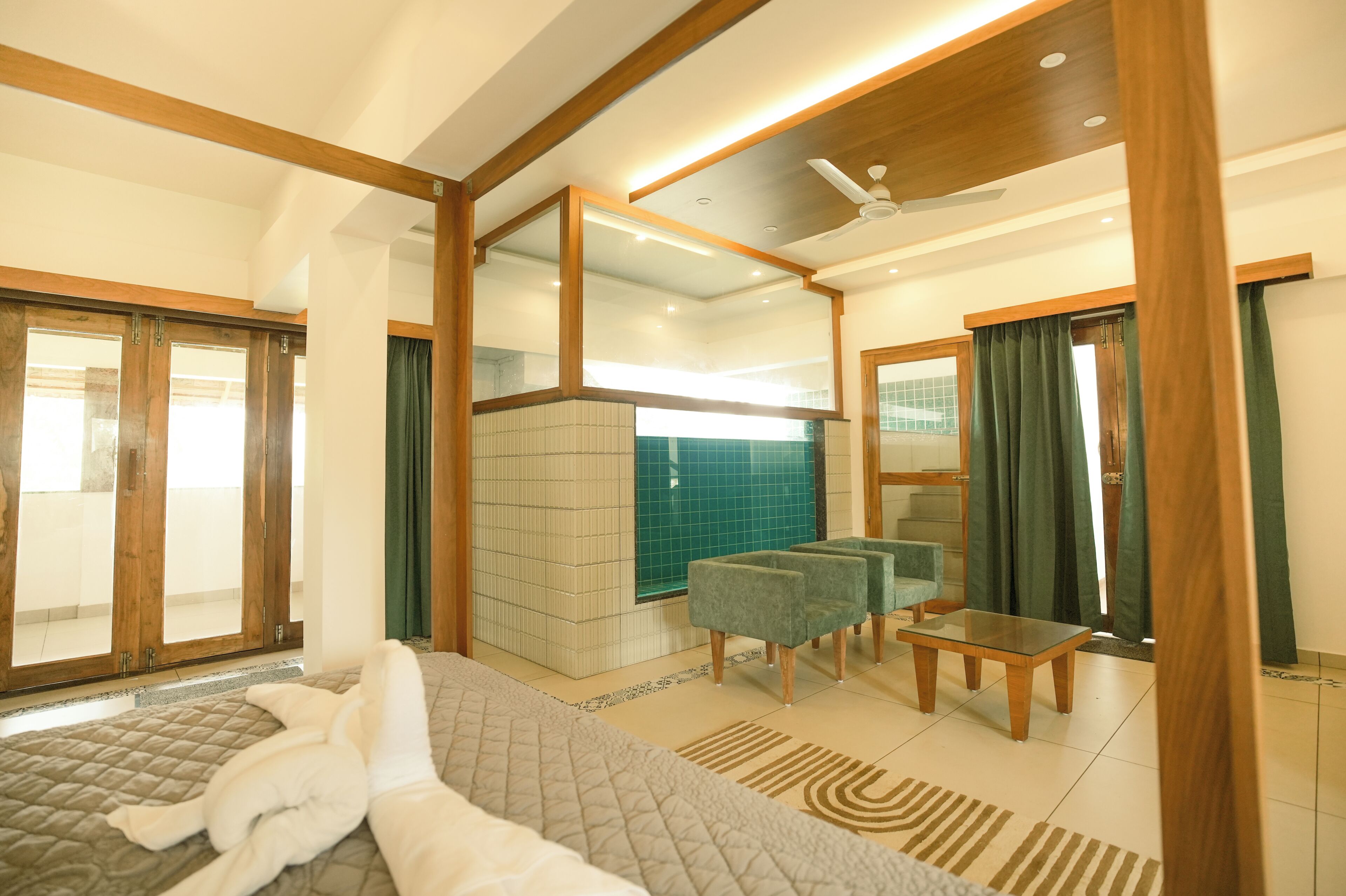 Une chambre d’hôtel comprenant un lit, un coin salon avec une table et des chaises, une salle de bain avec un miroir et un balcon avec vue.