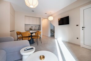 A modern living room with a sofa, a small white table, and a dining area with chairs. - Villa Merkur -apartment 2 (Makarska)