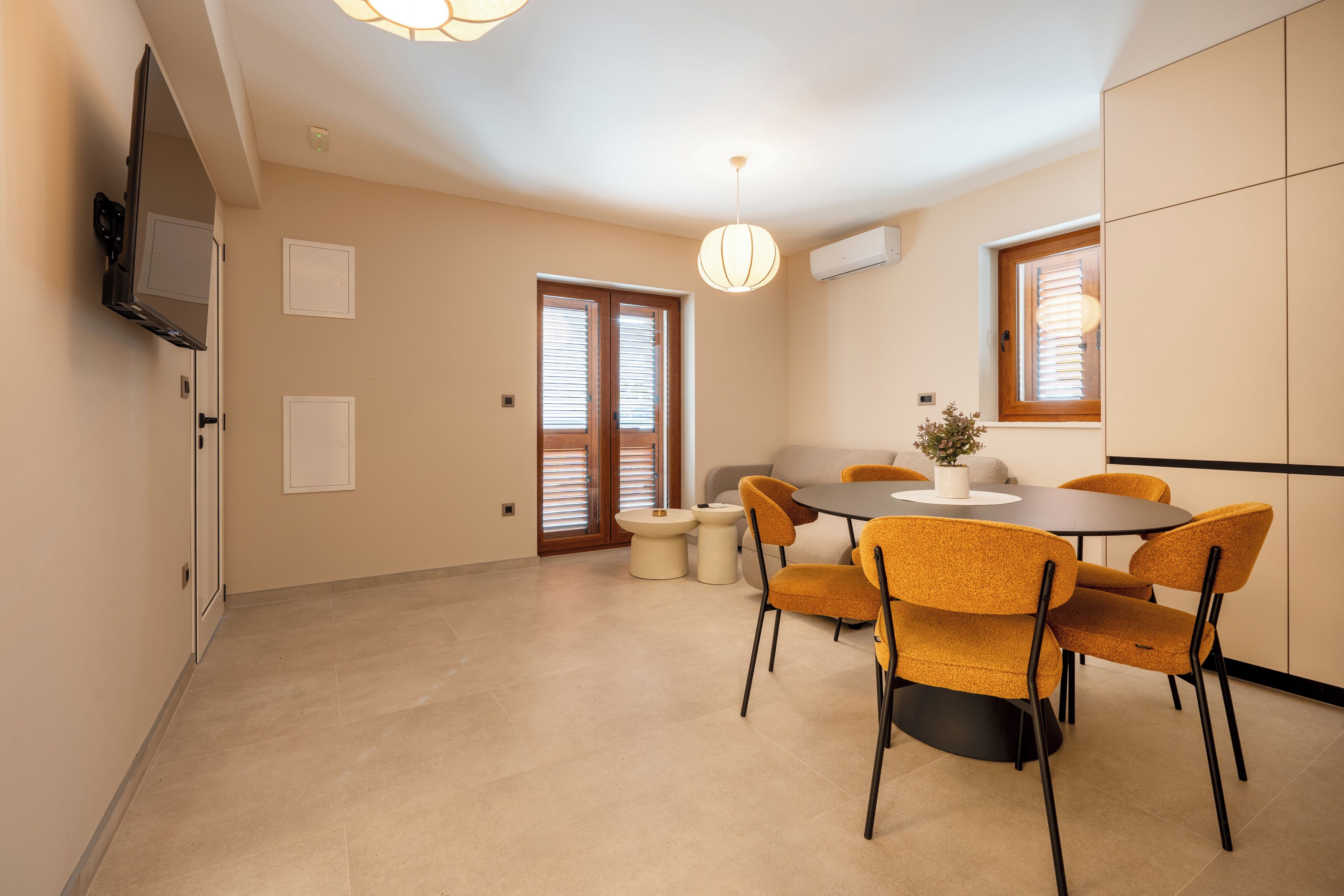 Un coin repas avec une table ronde, six chaises et un téléviseur fixé au mur.