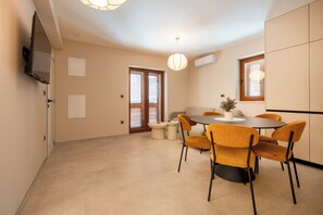 A dining area with a round table, six chairs, and a TV mounted on the wall. - Villa Merkur -apartment 2 (Makarska)