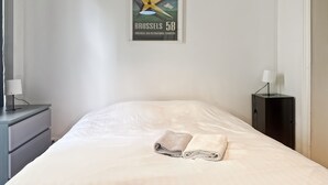 Una habitación de hotel con una cama, una mesita de noche, una lámpara, un cuadro en la pared y una ventana.