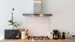 Una cocina con estufa a gas, cafetera y planta en maceta.