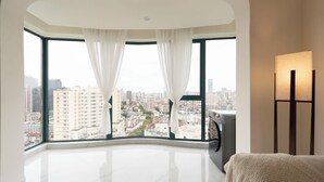 A modern hotel room with a large panoramic window, a flat-screen TV, and a standing lamp. - 3-bedroom apartment with high-rise balcony Near Xintiandi CBD200m to  Metro. (Shanghai)
