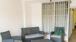 A room with wicker furniture, a tiled floor, and a sliding door.