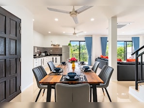 A modern dining area with a wooden table, black chairs, and a ceiling fan. - Luxurious Villa with Private Pool and Stunning Views (ตำบล ฉลอง)