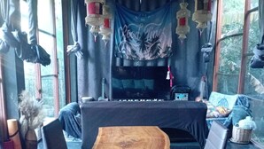 A room with a long wooden table, black leather chairs, a sofa, and a fireplace. - Crystal Jungle House - Rooftop mountain view (Ko Pha Ngan)