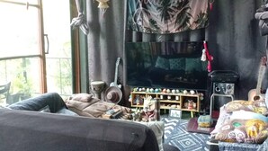 A room with a bed, a television, and various decorative items. - Crystal Jungle House - Rooftop mountain view (Ko Pha Ngan)