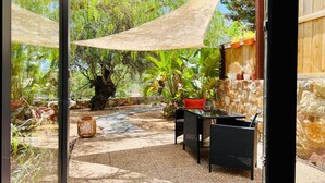 Eine Terrassesituation mit einer Steinmauer, Topfpflanzen und einem Tisch mit Stühlen.