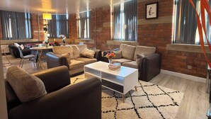 A modern living room with leather sofas, a coffee table, and a brick wall. - Winter stays, Pool, Wi-Fi, Parking, 3double beds (Bradford)
