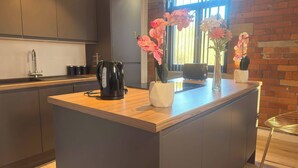 A modern kitchen with a central island, a kettle, and decorative flowers. - Winter stays, Pool, Wi-Fi, Parking, 3double beds (Bradford)