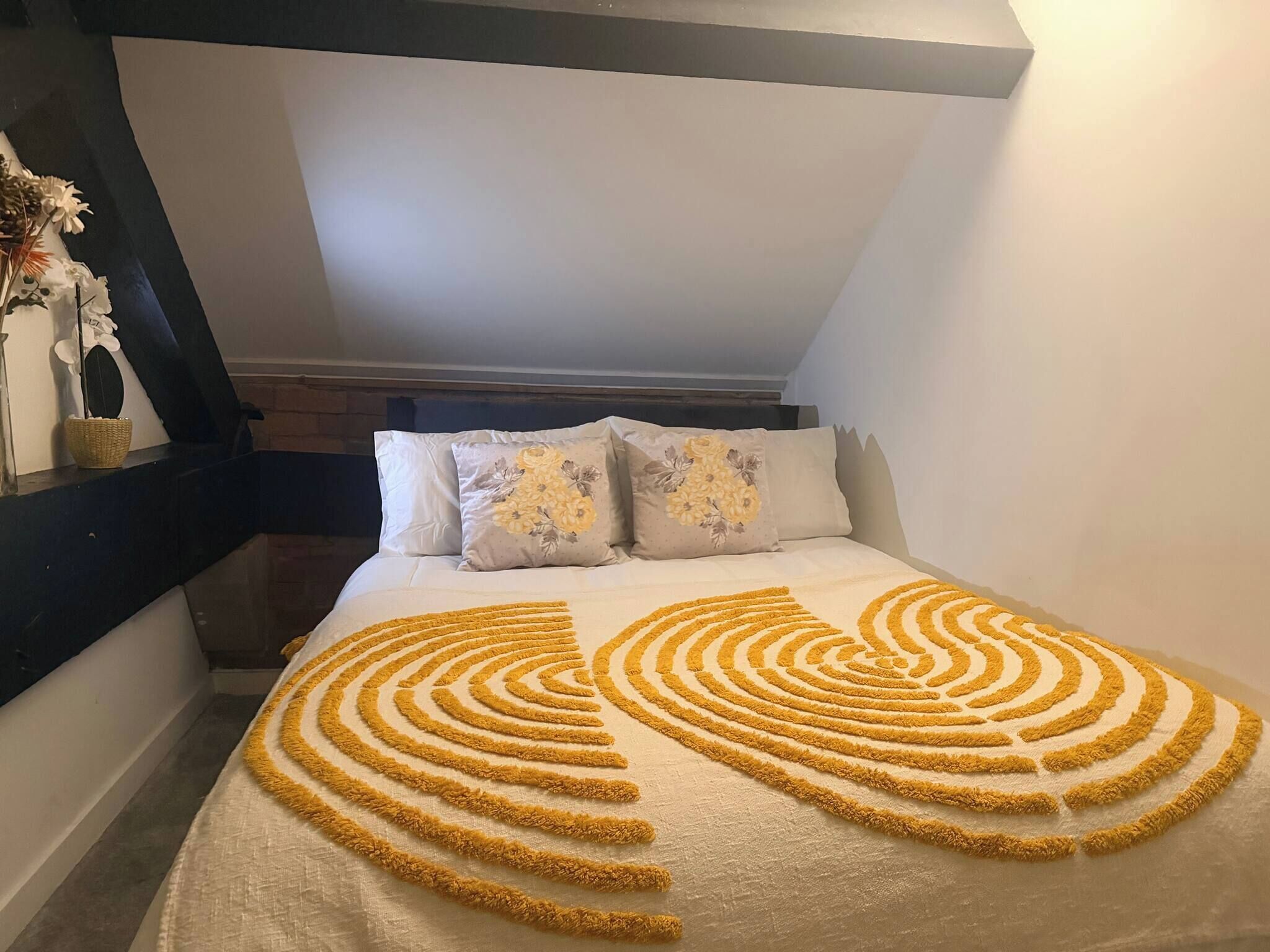 A bedroom with a bed, pillows, and a decorative pattern on the bedspread.