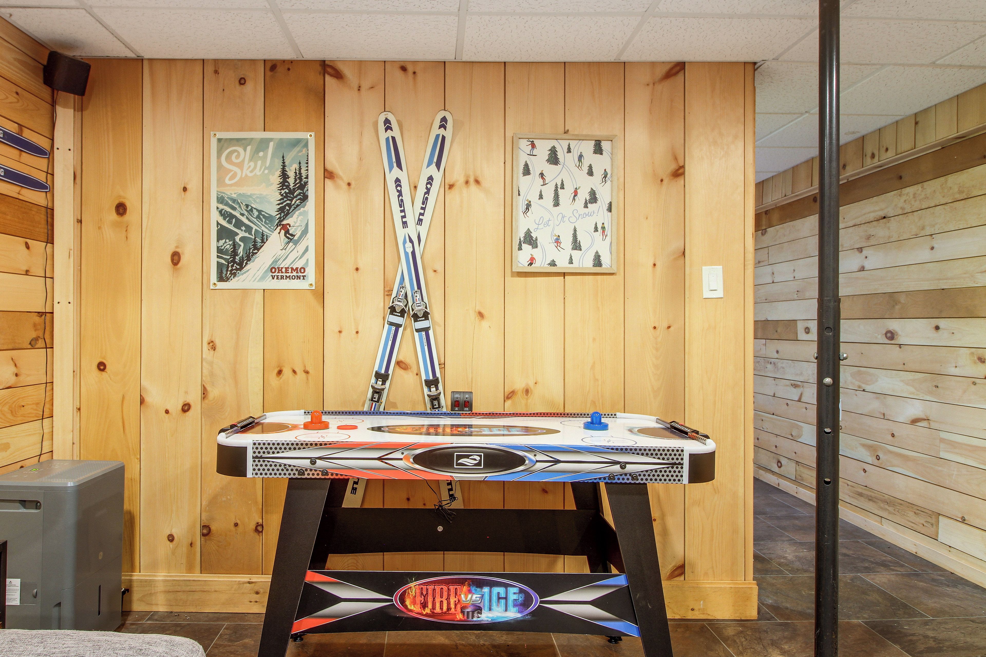 A room with wooden walls, a table with a table tennis table, and two posters on the wall.