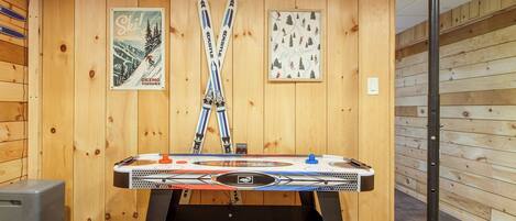 A room with wooden walls, a table with a table tennis table, and two posters on the wall.