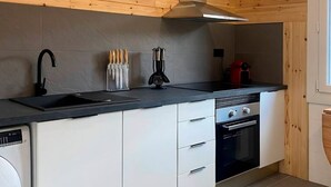 A modern kitchen with a black countertop, white cabinets, a built-in oven, and a stainless steel range hood. - Rural apartment in Cal Rosal, Berga - Air conditioning and nature (Avià)