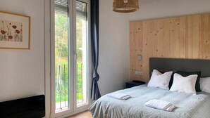 A bedroom with a bed, a bedside table, a nightstand, a window with a view, and a wall-mounted light fixture. - Rural apartment in Cal Rosal, Berga - Air conditioning and nature (Avià)