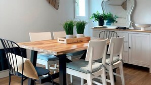 A dining area with a wooden table, white chairs, a potted plant, and a decorative mirror on the wall. - Rural apartment in Cal Rosal, Berga - Air conditioning and nature (Avià)